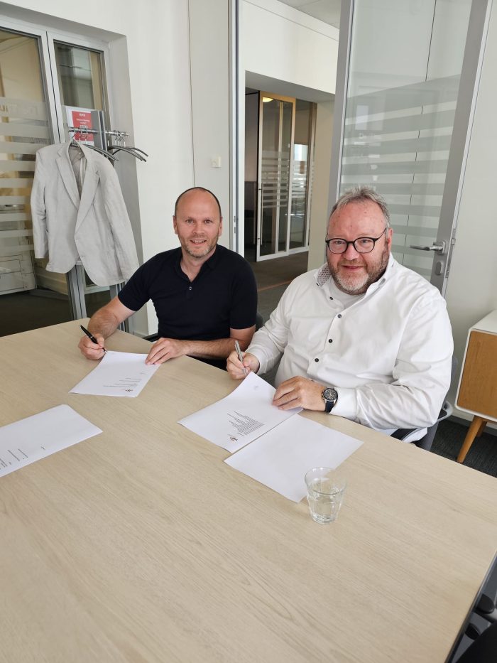 Mark Plaisier (links) en Dick Mol (rechts) ondertekenen de aanneemovereenkomst.
